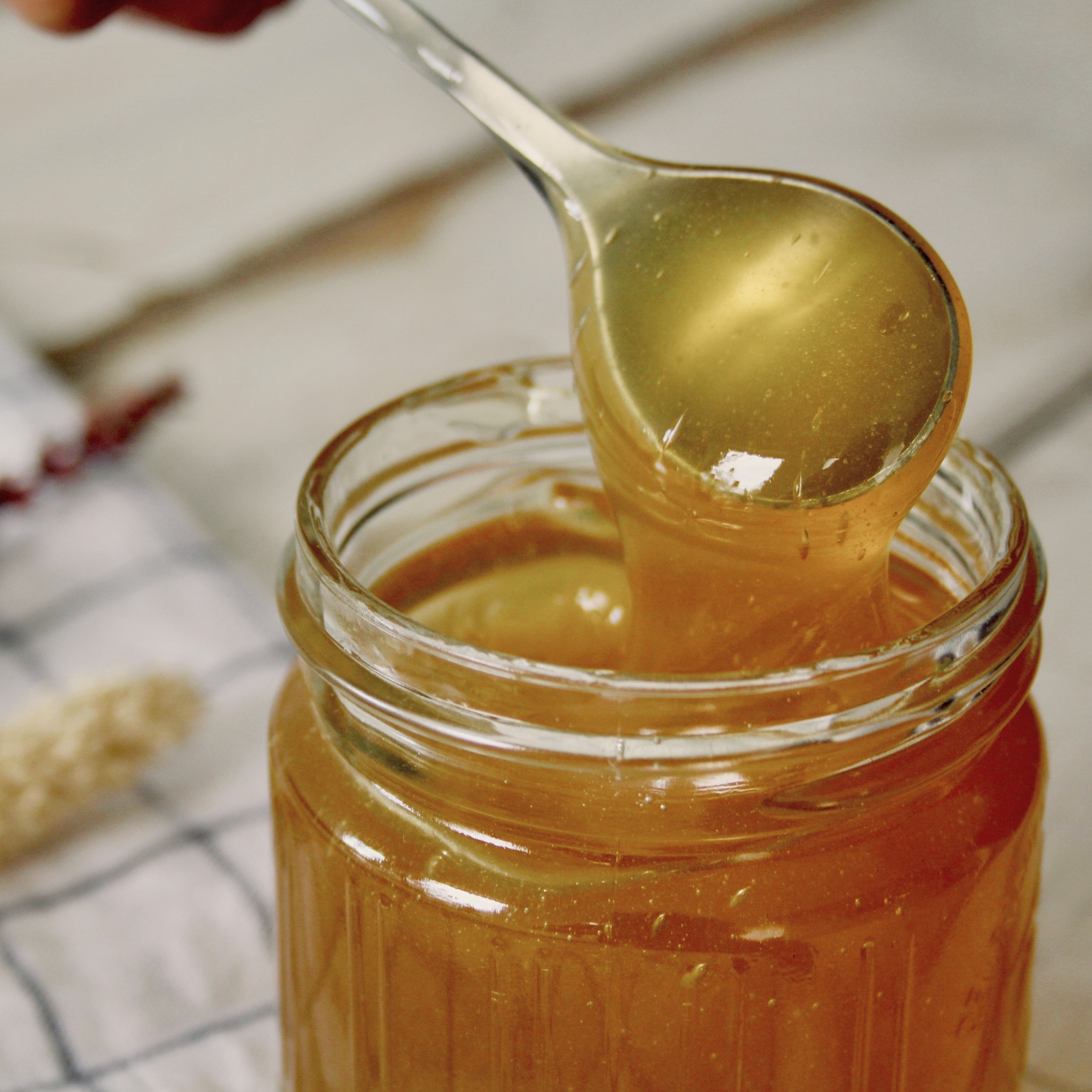 A spoon dipping into a glass jar of pure honey.