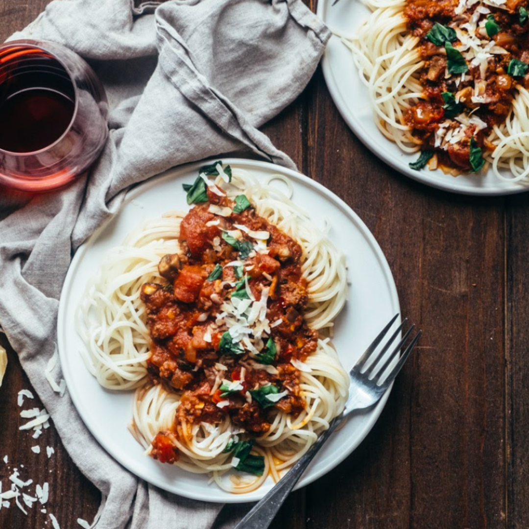 An overhead image of two plates of spaghetti bolognese made with NIKU Farms pasture raised meat.