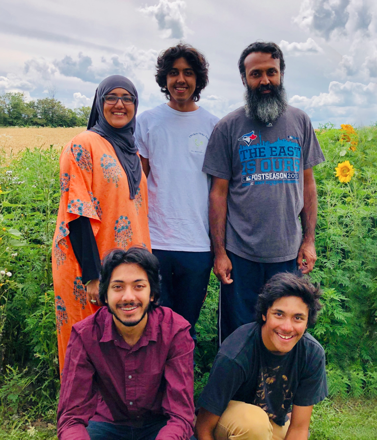 A family of farmers in pasture, smiling at the camera.