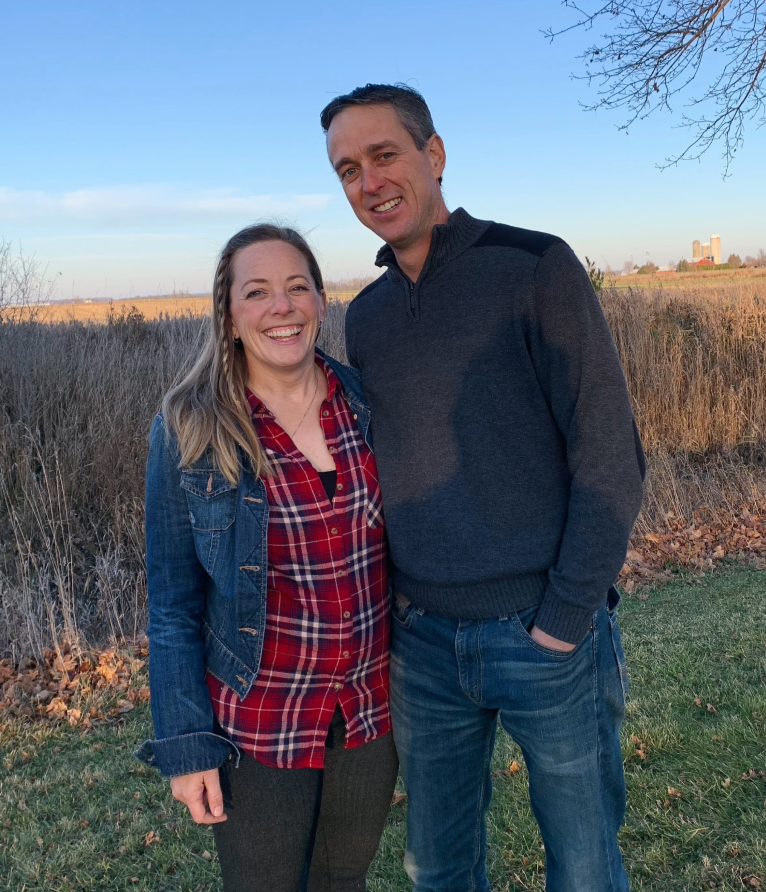 Two farmers in pasture smiling at the camera.