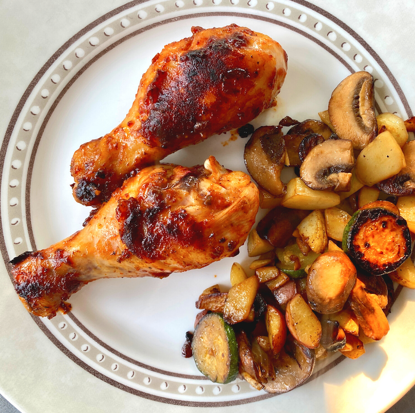 Two spicy pasture raised chicken drumsticks served with zucchini and mushrooms.
