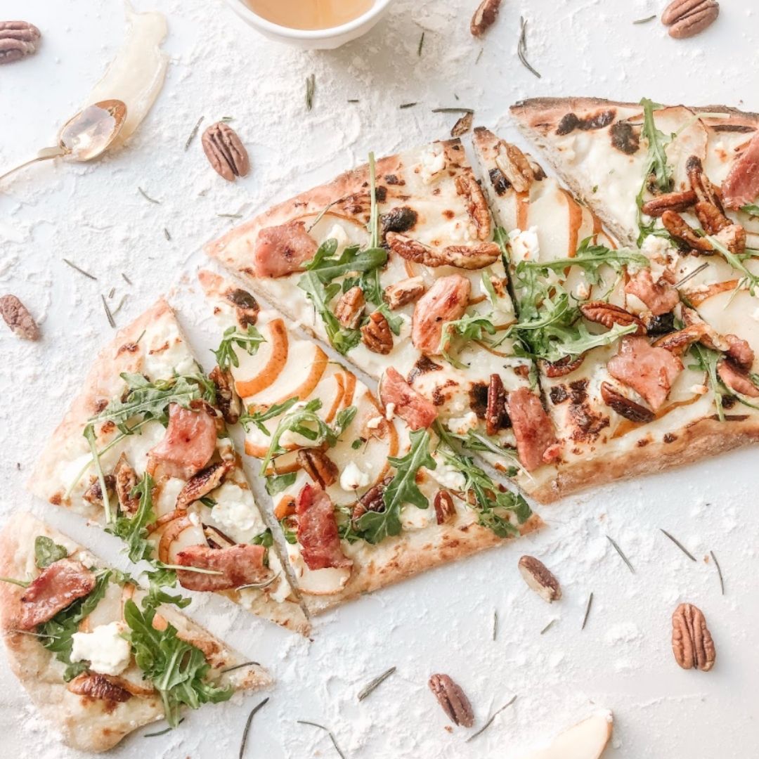 A flatbread pizza with arugula, pecans, apple and goat cheese.