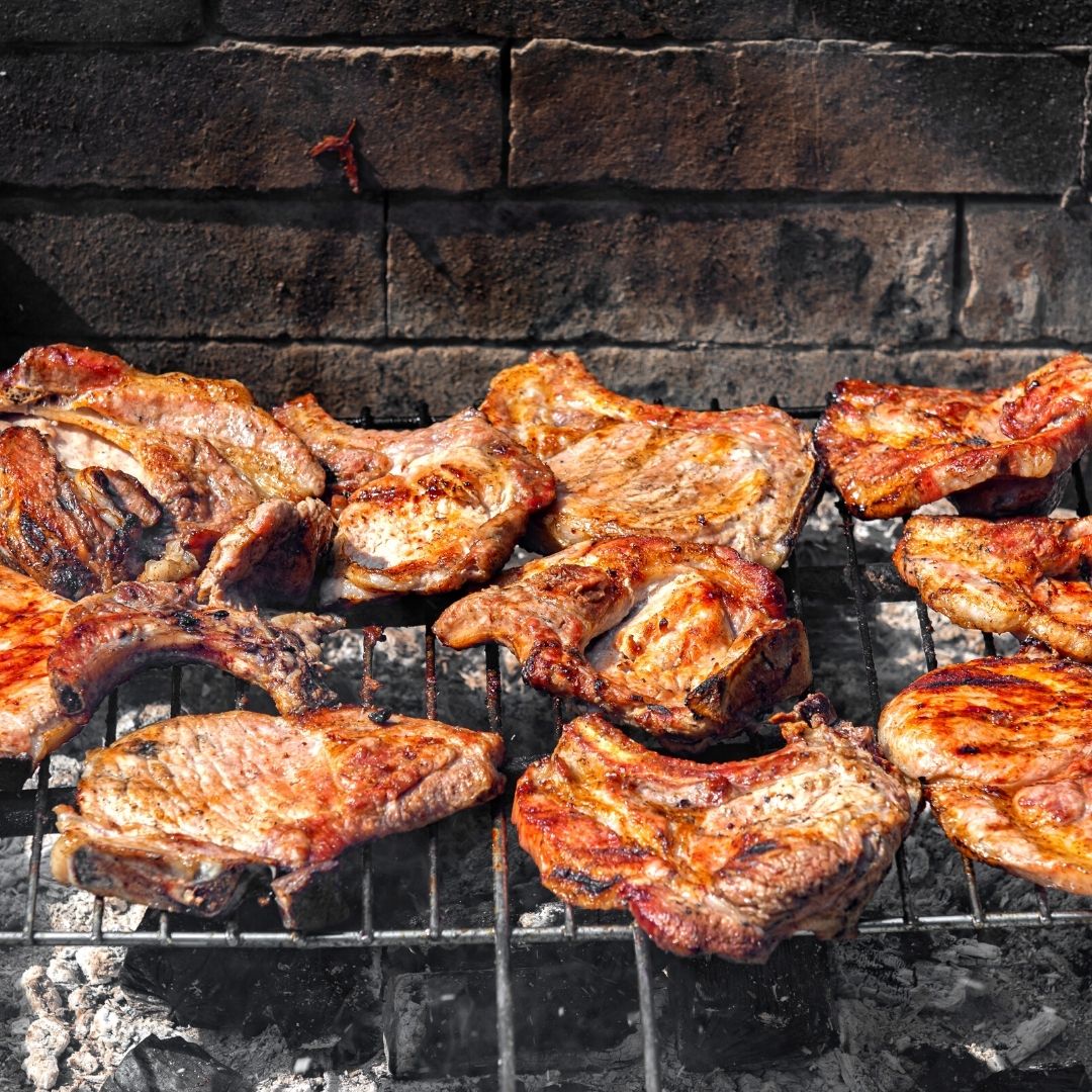 Various types of meat cooking on the grill.